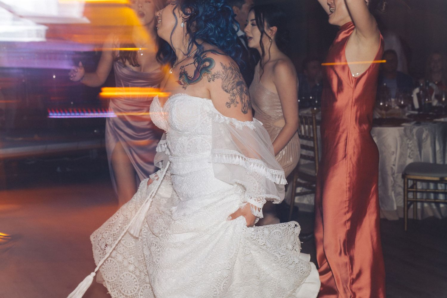 Guests dancing at a wedding reception celebration with the bride in a white gown on the dance floor.