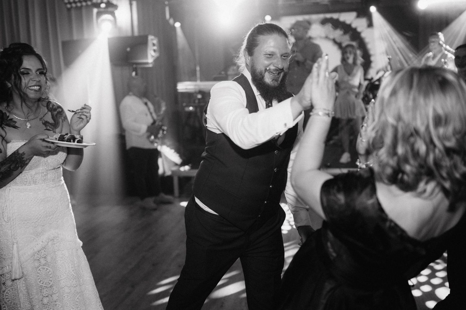 People dancing and celebrating joyfully at a nighttime party or celebration event on a darkened dance floor.