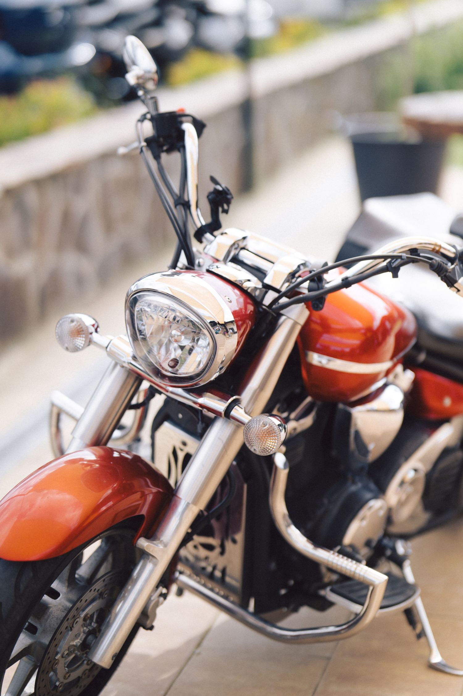 Close-up view of an orange motorcycle's front end showing chrome handlebars, headlight and fuel tank.