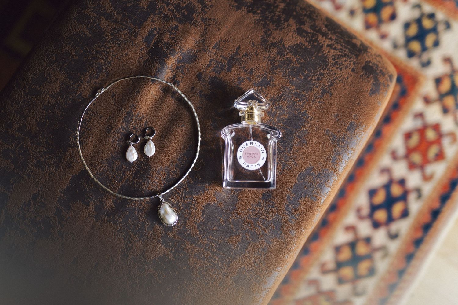 Silver jewelry collection including delicate earrings and hoop necklaces displayed on brown textured surface.