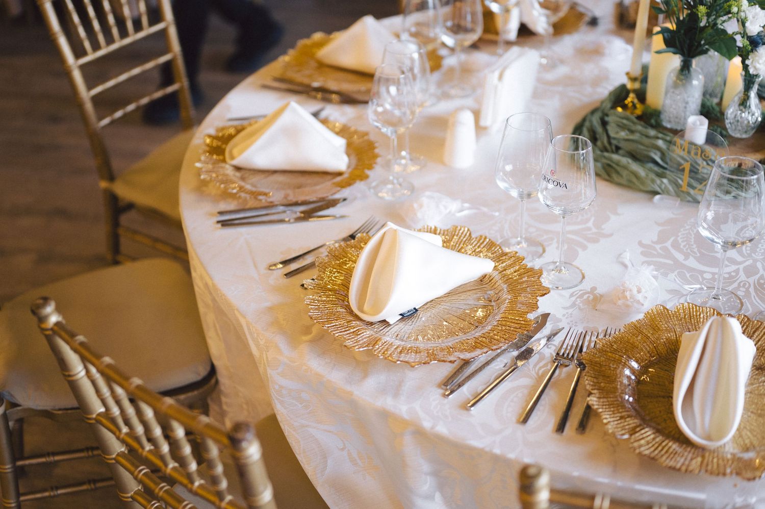 White table settings with elegant glassware and gold accents create an upscale banquet dining atmosphere.