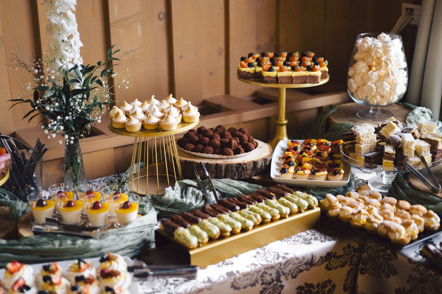 Elegant dessert table display with various petit fours, pastries, and sweets arranged on decorative stands and platters.