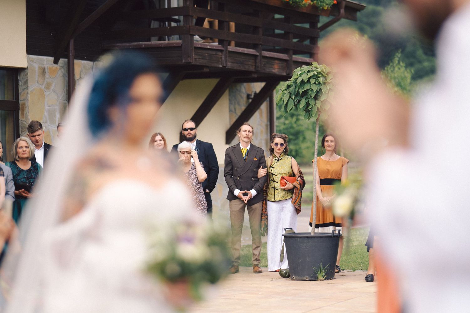Wedding guests gathered at outdoor venue with beautiful natural backdrop and rustic wooden details.