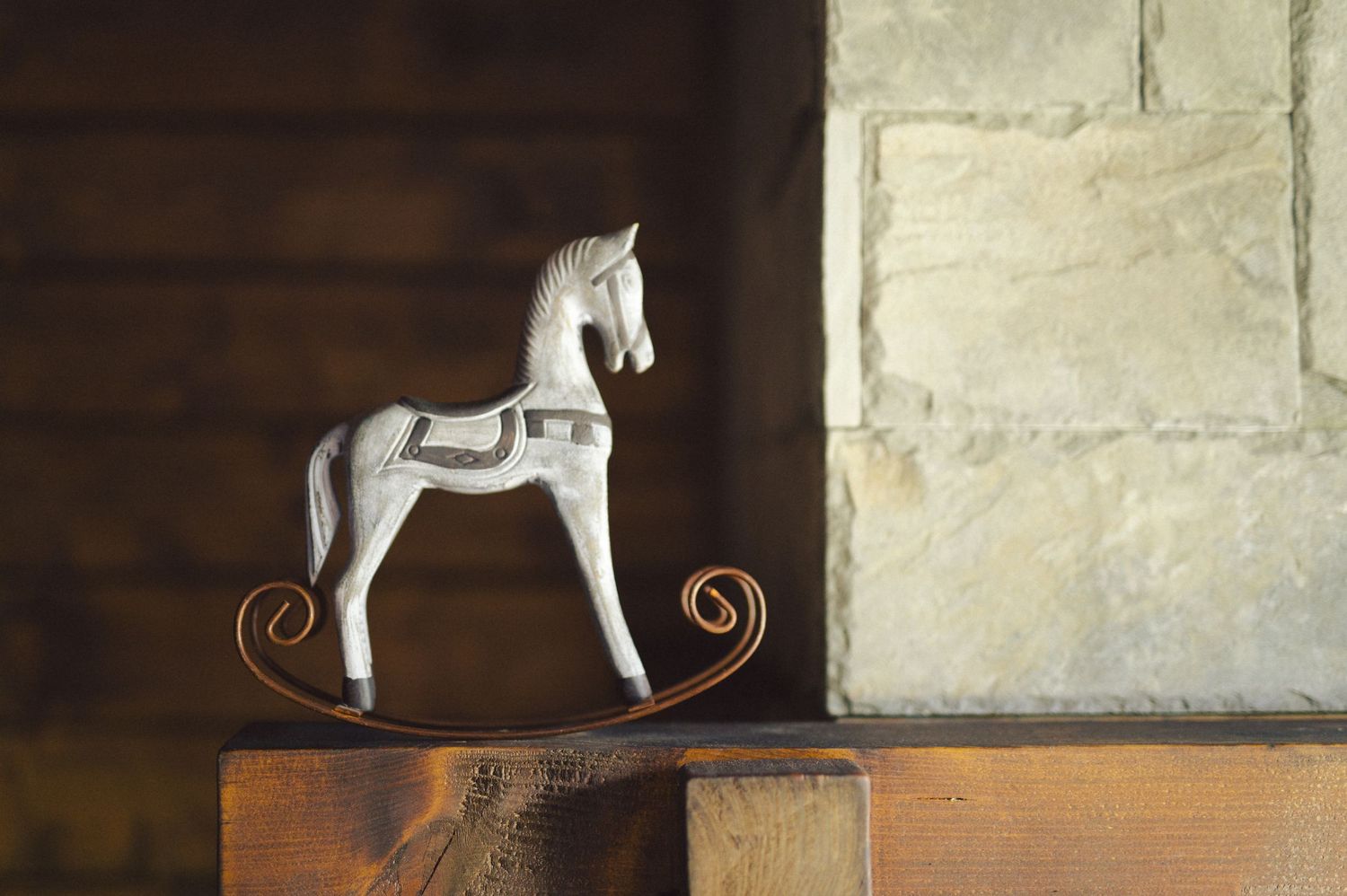 A collection of vintage rocking horse toys on wooden bases displayed in a rustic indoor setting.