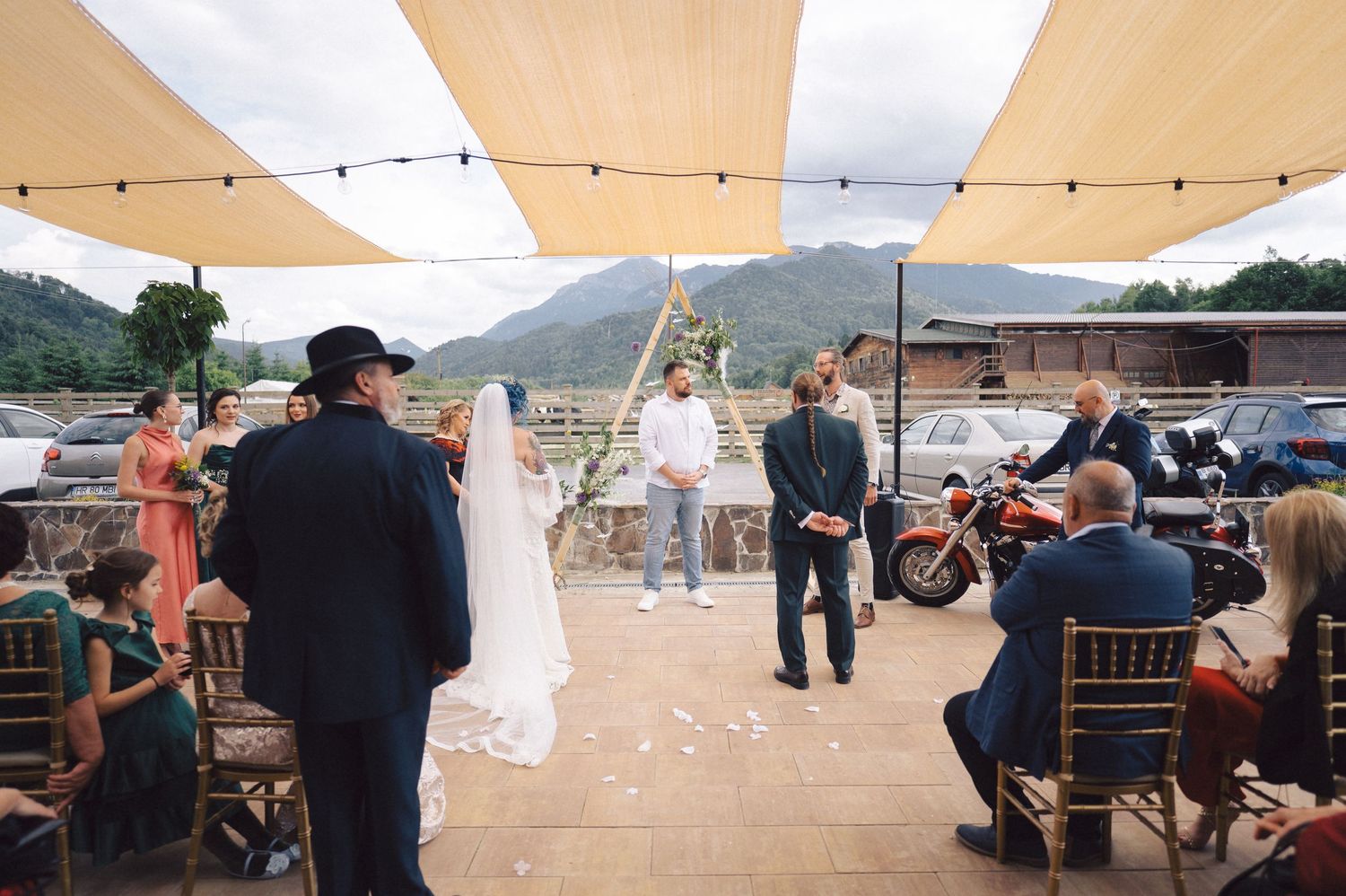 String lights illuminate an outdoor wedding reception venue with mountainous backdrop at sunset.
