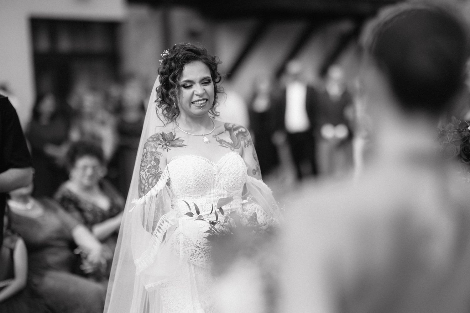 A happy bride in a white lace wedding dress dances joyfully during an outdoor celebration.
