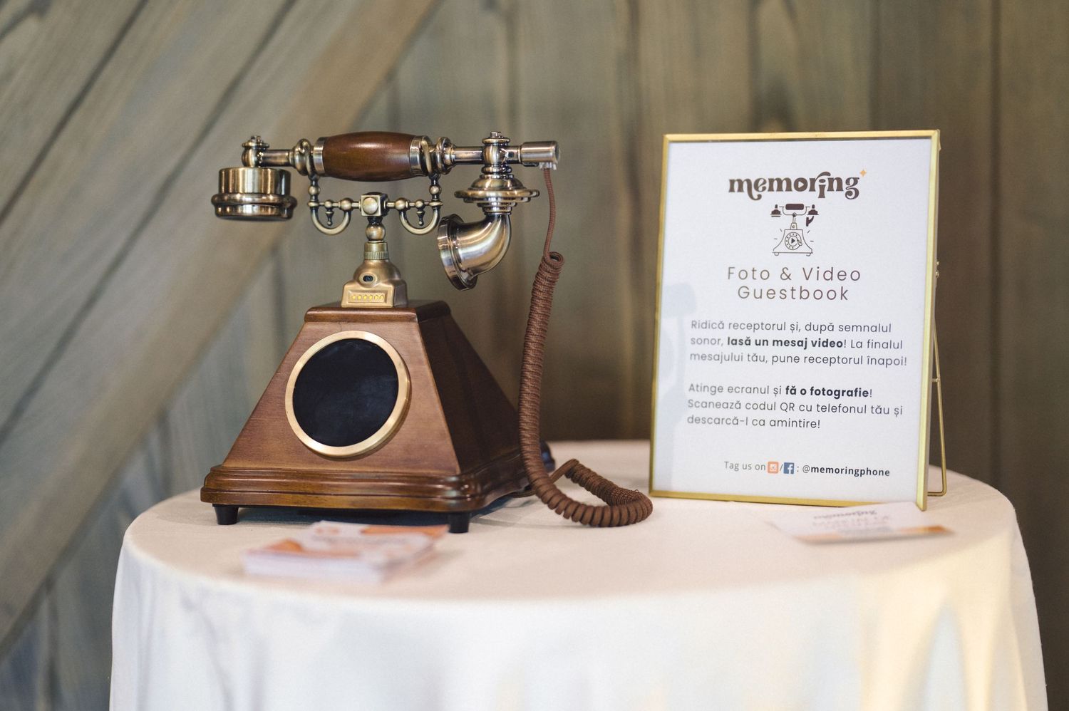 Vintage copper-toned rotary telephone displayed on white tablecloth next to reception sign at event.