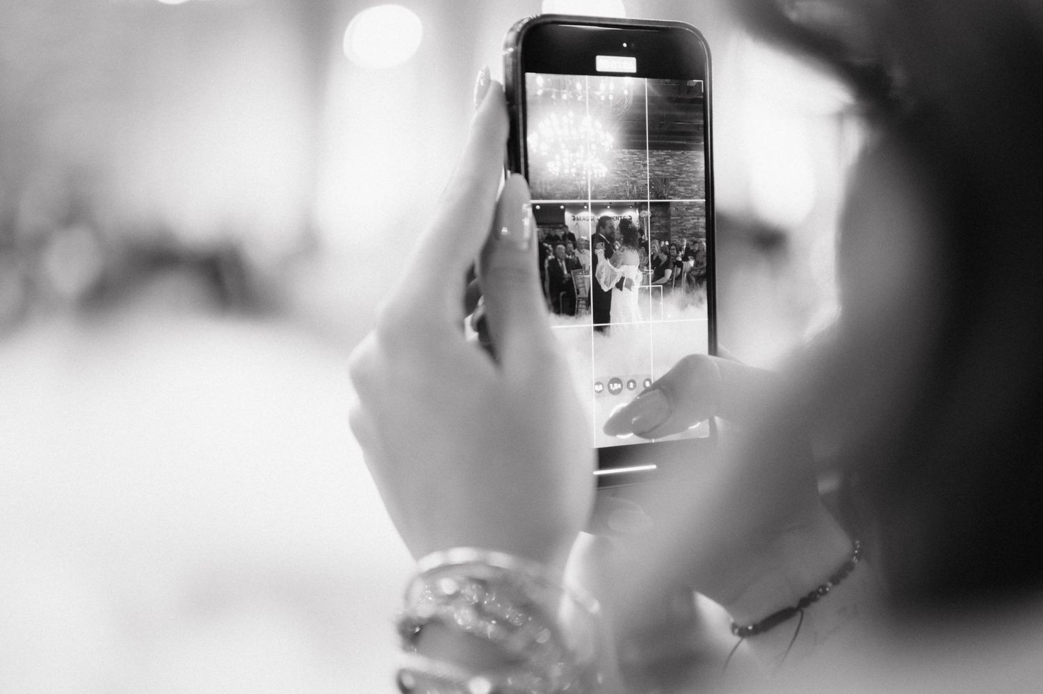 Someone holding a smartphone capturing a black and white photograph during an event.