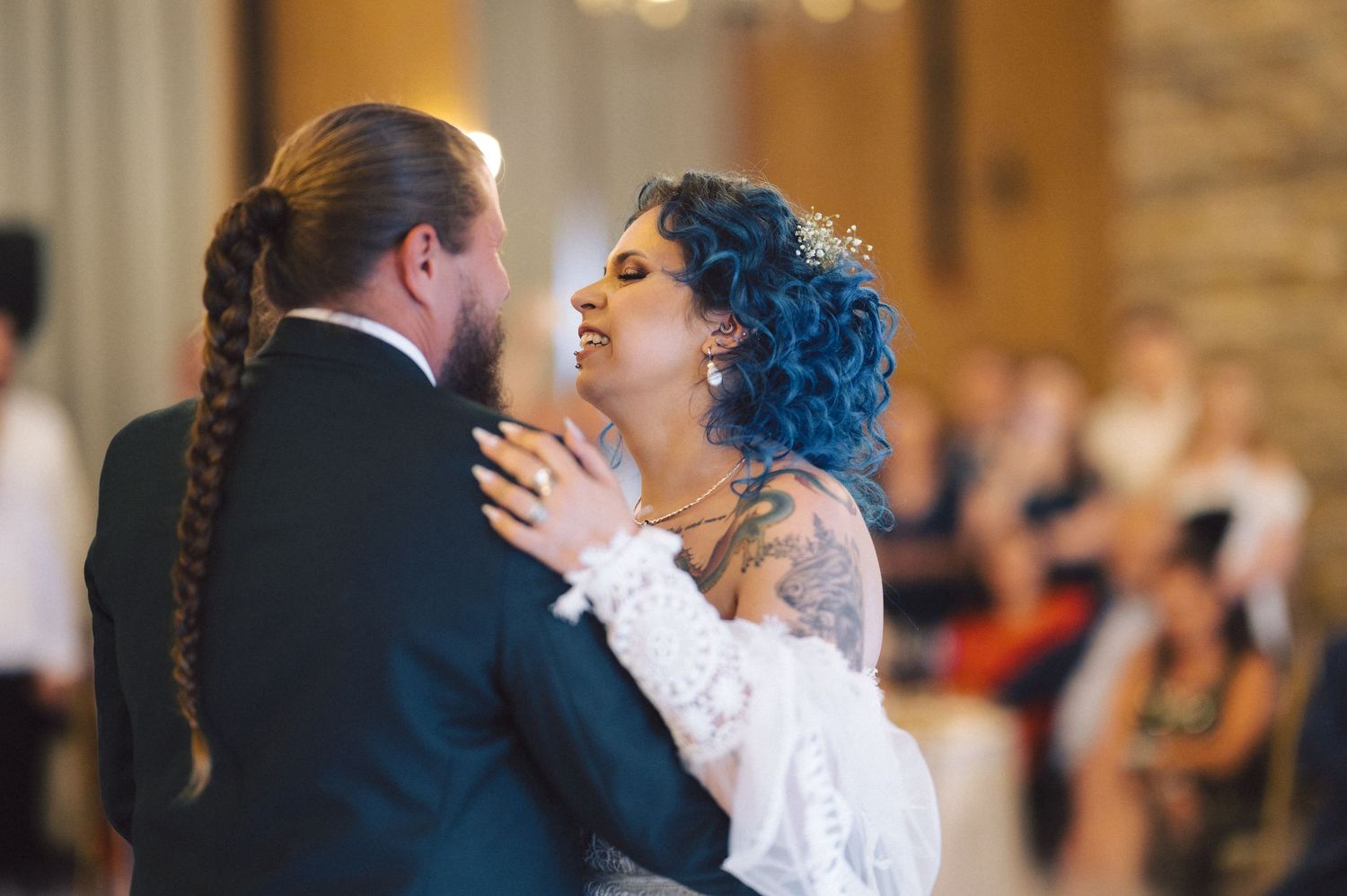 A couple shares a tender moment during their first dance at an elegant indoor wedding reception.
