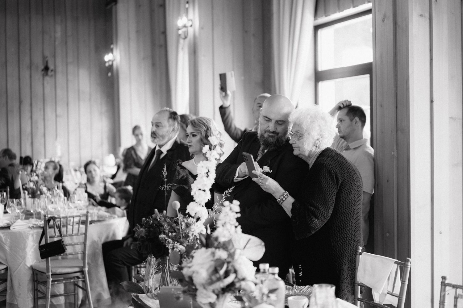 Wedding guests raising their glasses in celebration at an elegant black and white reception dinner.