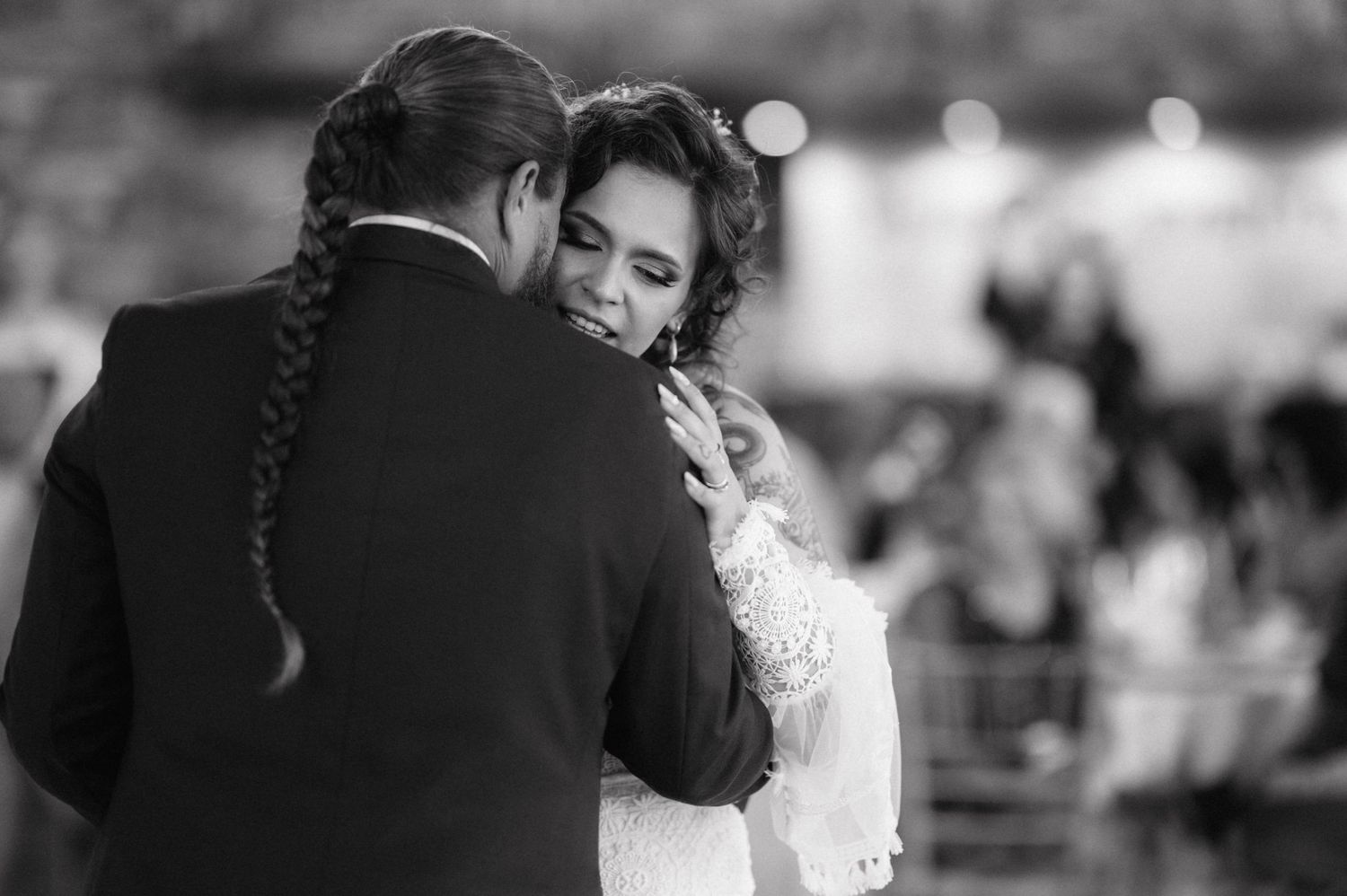Joyful newlyweds embrace during a lively group dance celebration at their wedding reception.