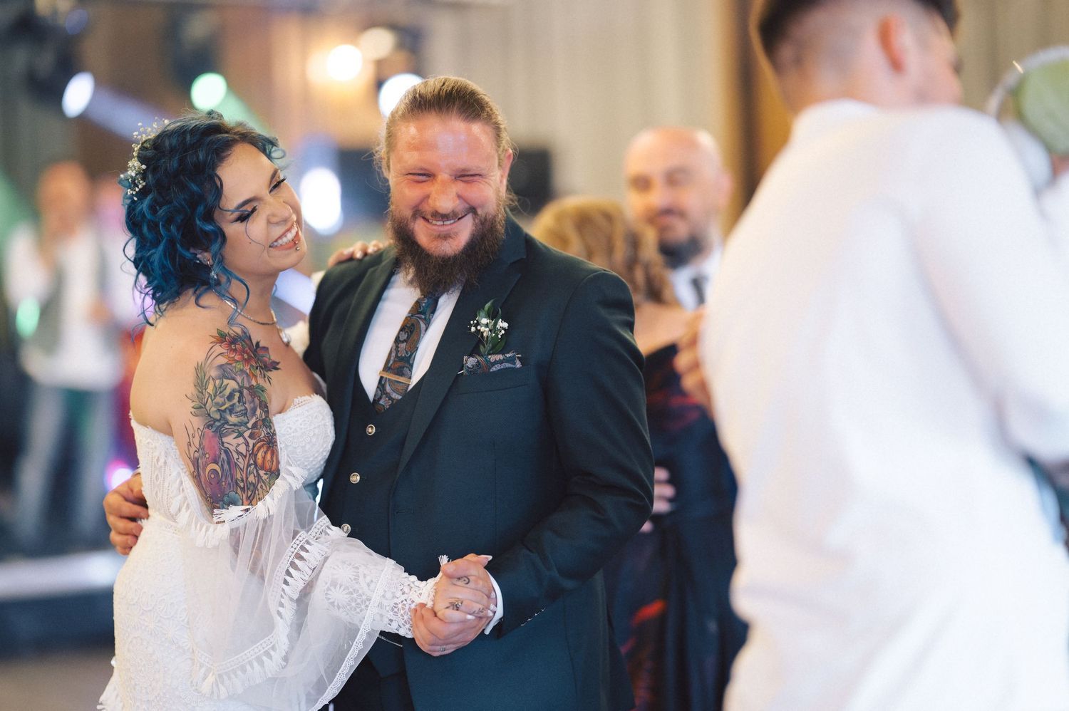 A couple shares their first dance at a wedding reception with guests watching in the background.