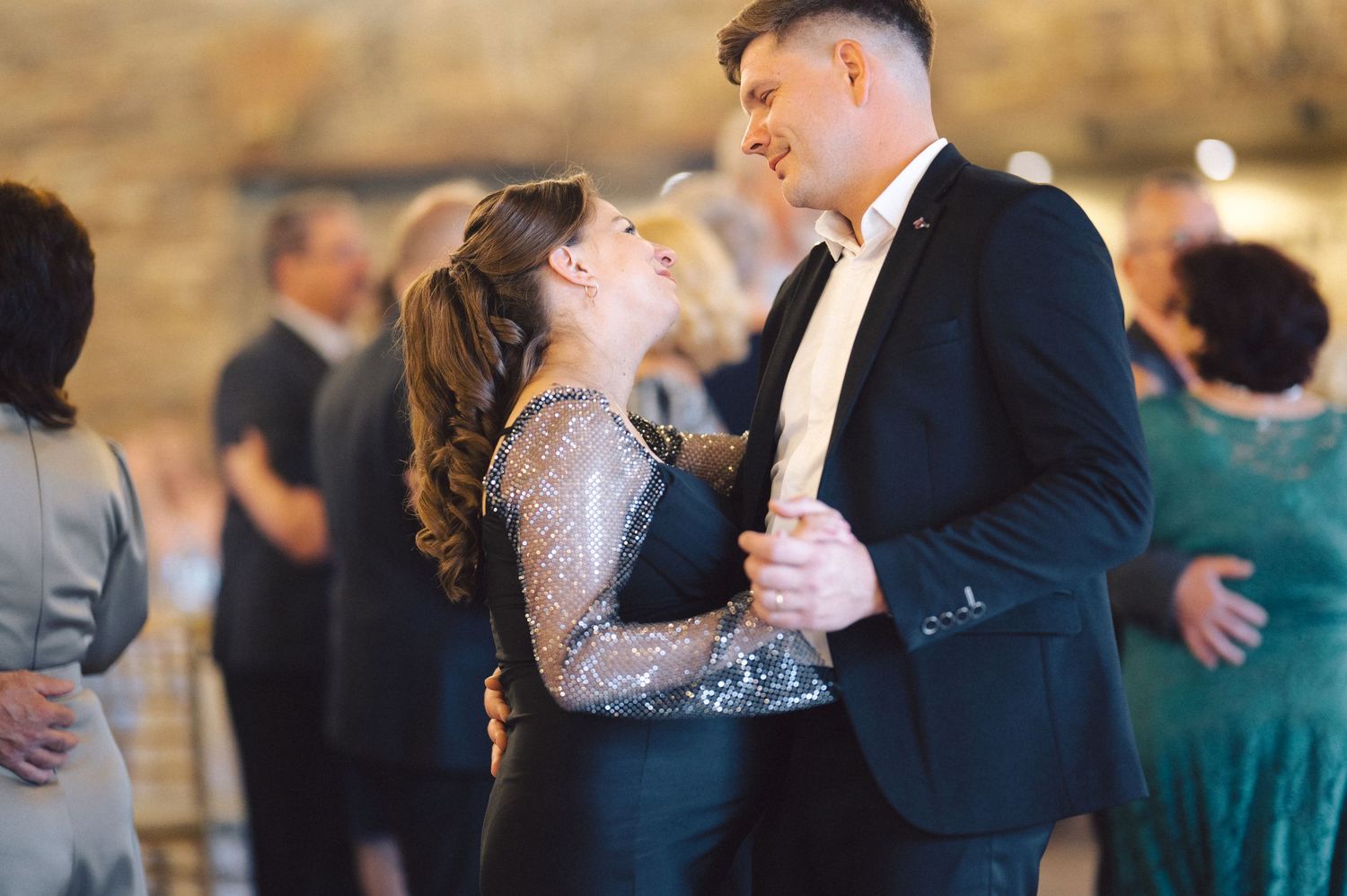 Couples dance together at an elegant evening wedding reception with soft lighting and formal attire.