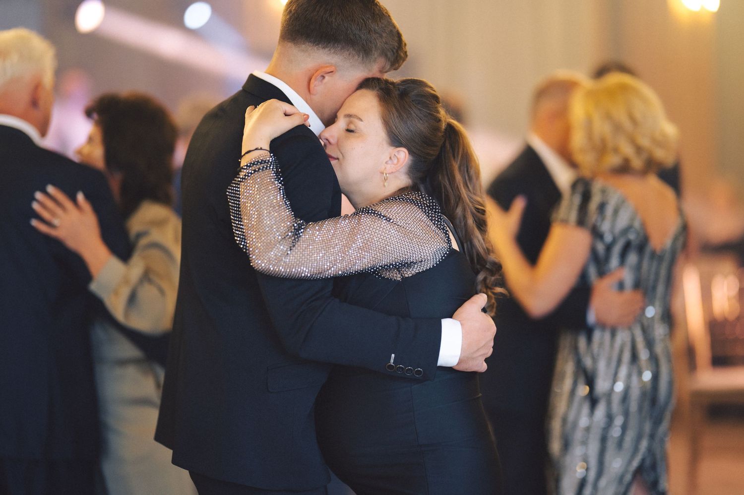 Couples dance gracefully together during an intimate ballroom dance event with warm ambient lighting.