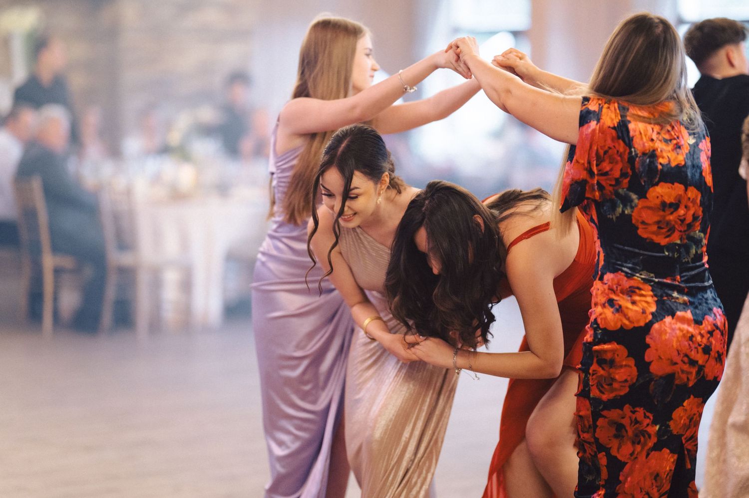 Couples dance together in pairs at a social dance event in a dimly lit ballroom with fog or haze.