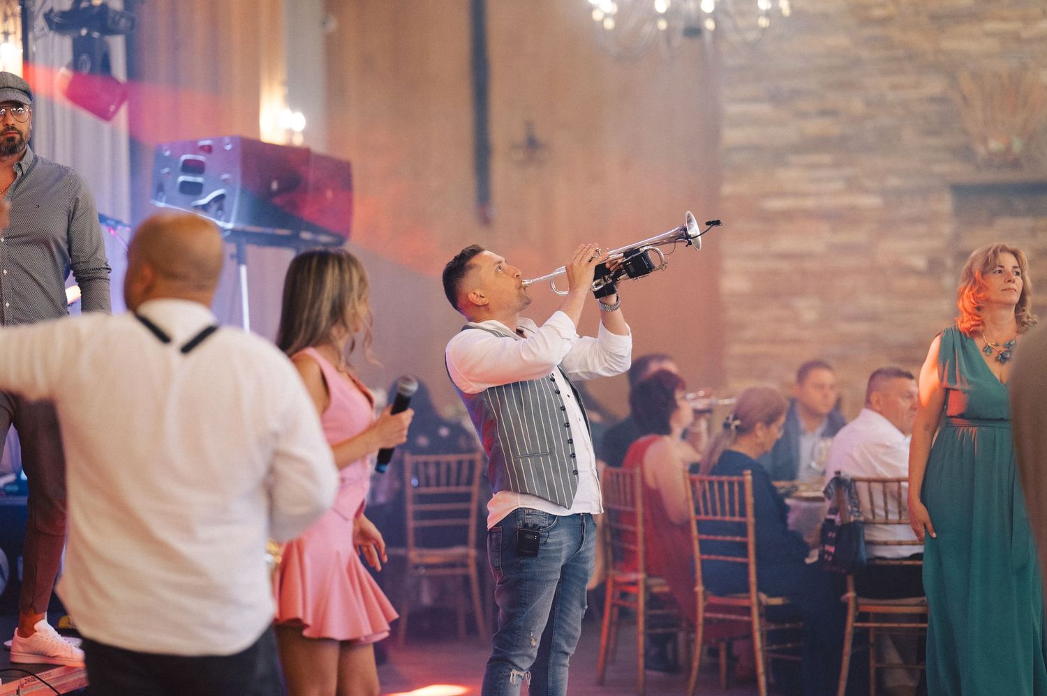 Wedding guests enjoying themselves on the dance floor at an indoor reception venue with exposed brick walls.