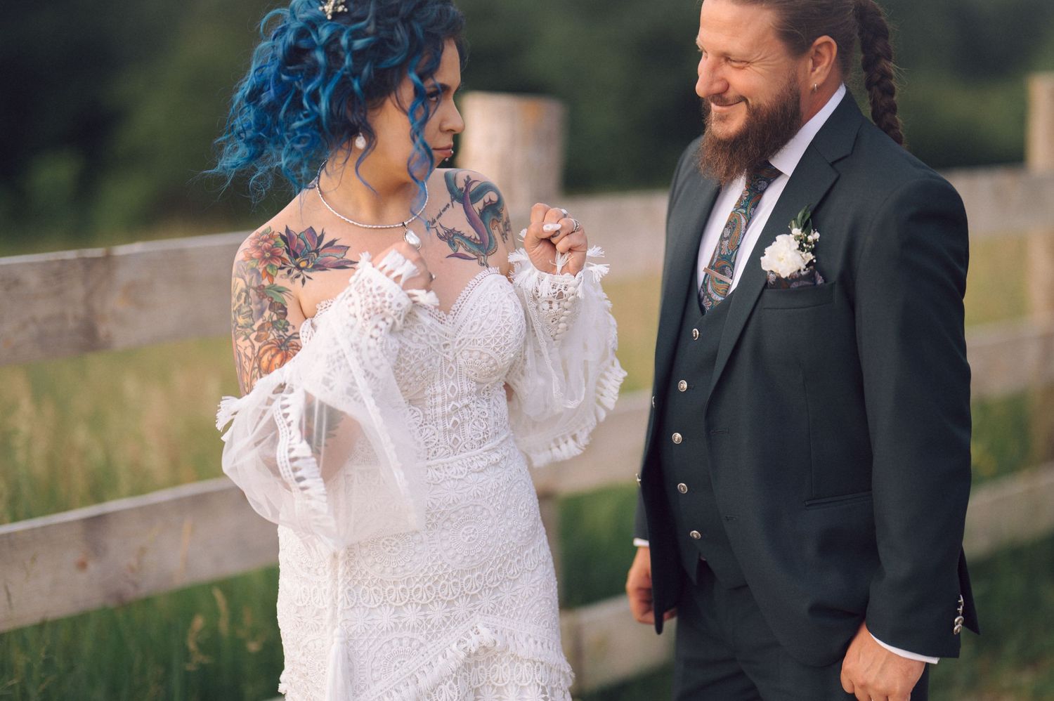 A couple shares joyful moments together outdoors, with the bride wearing a white lace dress and groom in a dark suit.