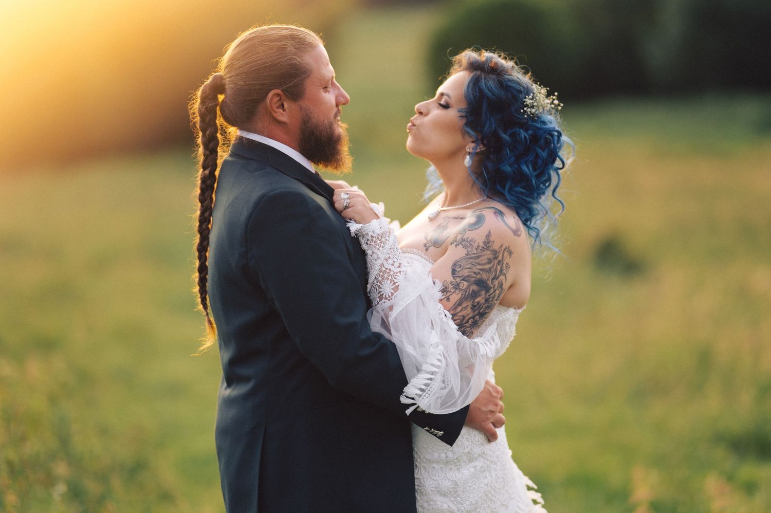 Newlywed couple shares romantic moments in a golden sunlit meadow during sunset photoshoot.