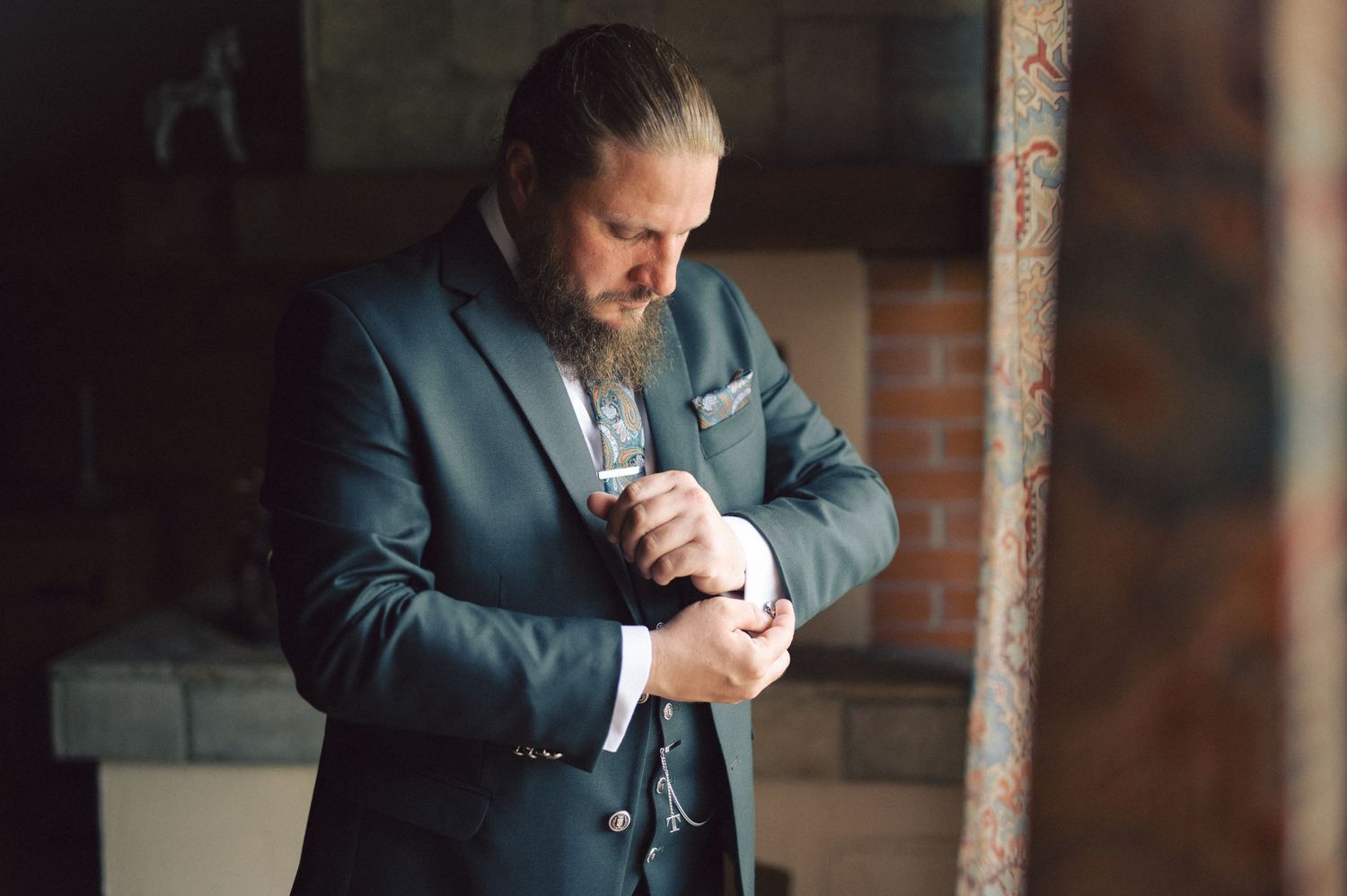 A person in a blue suit holds a newborn baby against brick wall in an emotional portrait session.