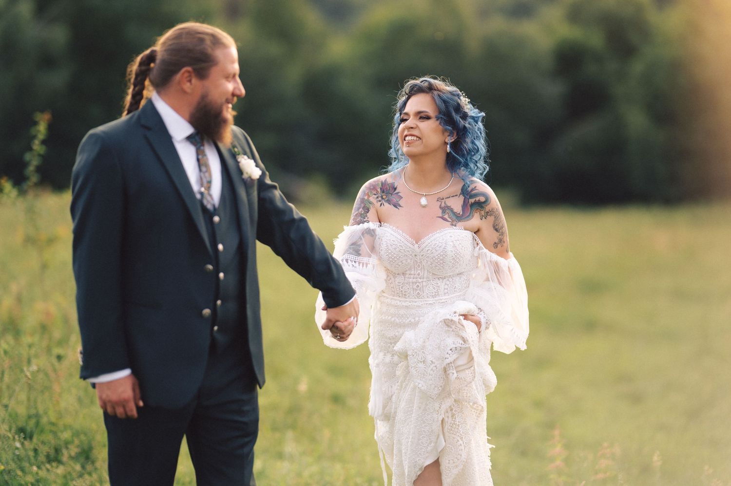 A happy couple enjoys a candid moment together in a sunlit outdoor field on their wedding day.