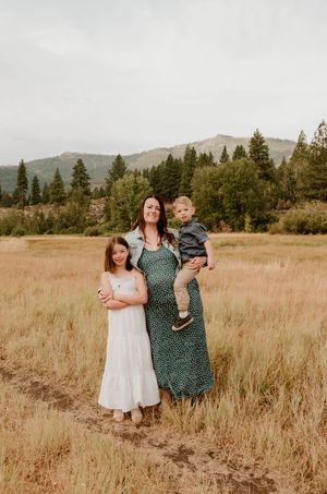 People enjoying a golden autumn day in a mountain meadow with tall grasses and evergreen trees in the background.