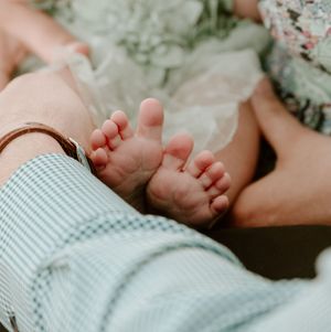 Close up shot of tiny newborn baby feet wrapped in soft blue and white striped blanket.