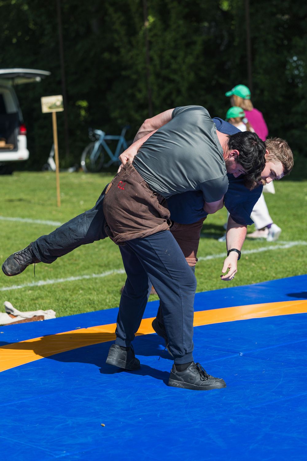 Sequence showing person falling forward onto blue padded mat during outdoor sports or training activity.
