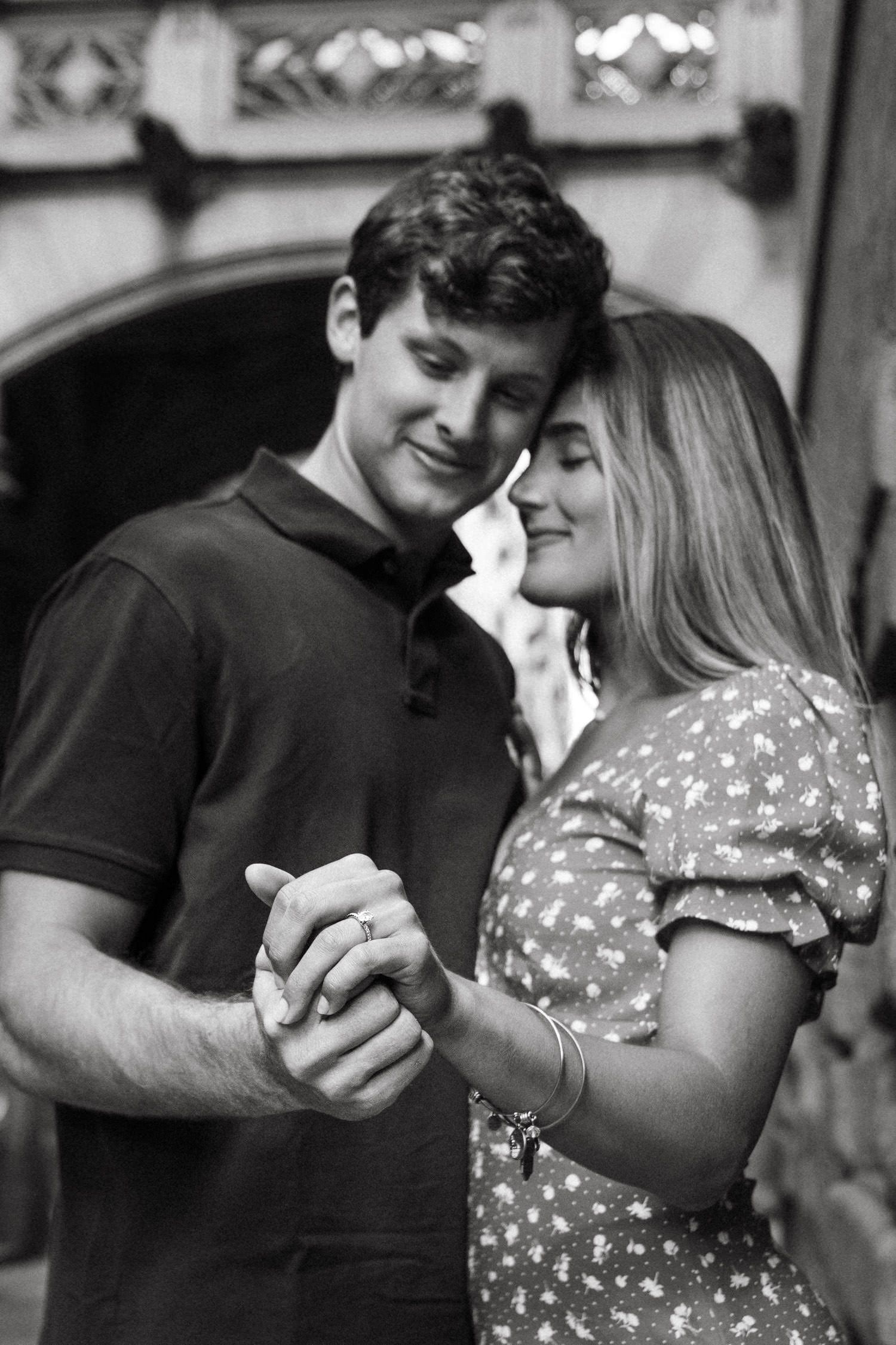 Black and white photo of couple sharing intimate moments in historic setting.