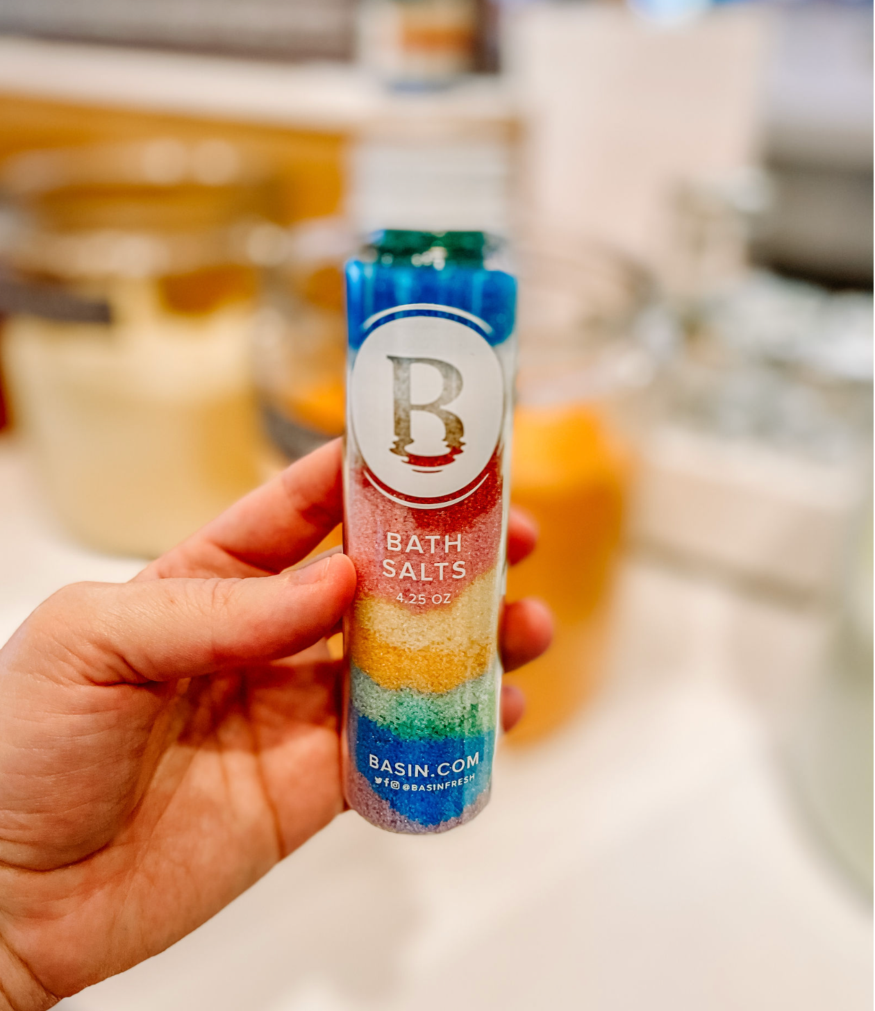 Blue and white cylindrical bottle labeled with letter B being held against blurred background.
