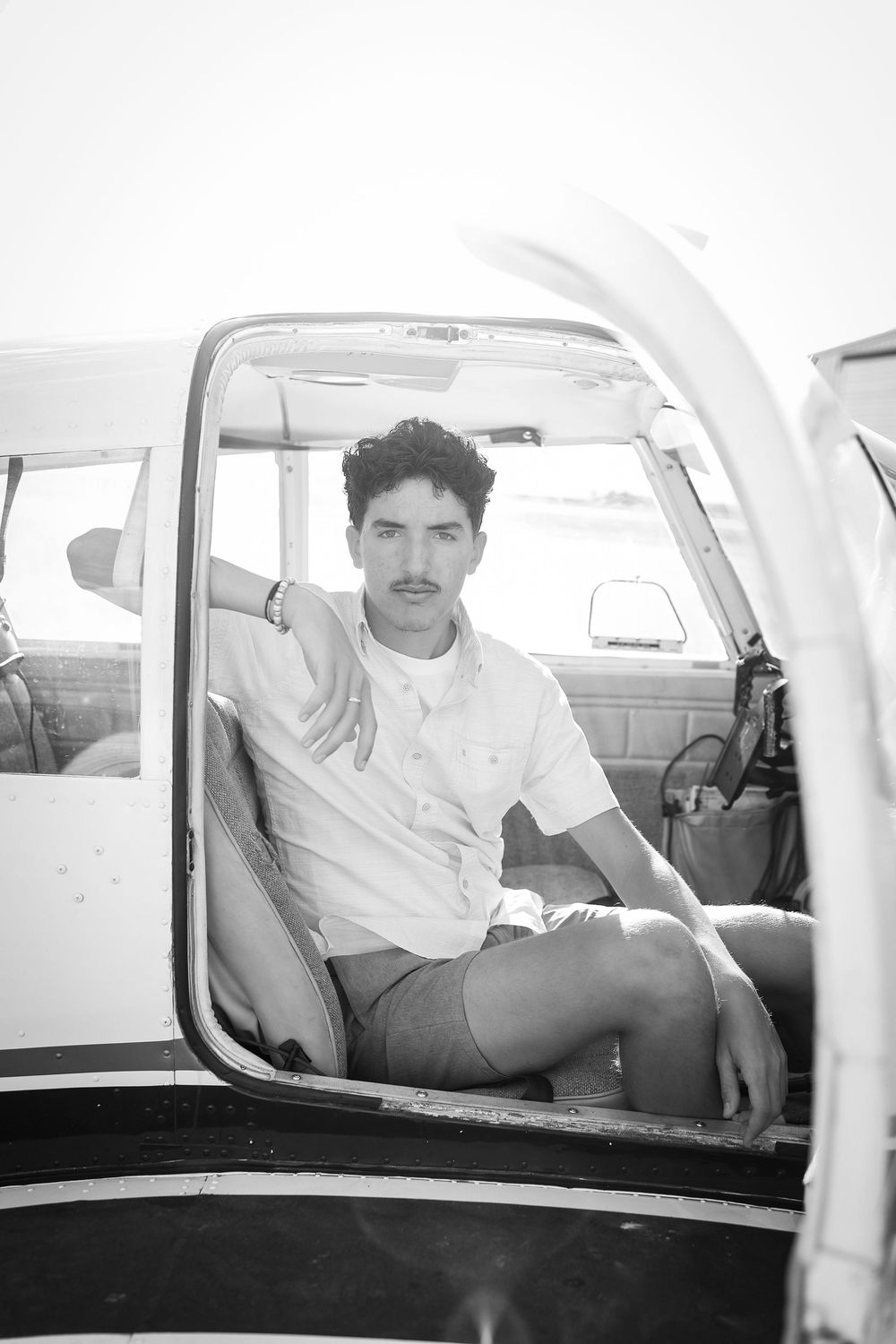 A black and white photo sequence of someone seated in a small aircraft cockpit, viewed from different angles.