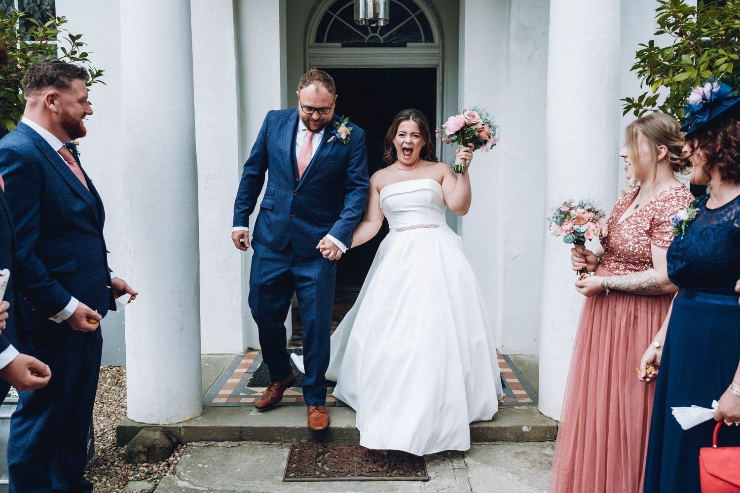 A joyous wedding ceremony moment as a couple exchange vows while guests smile and laugh in the background.