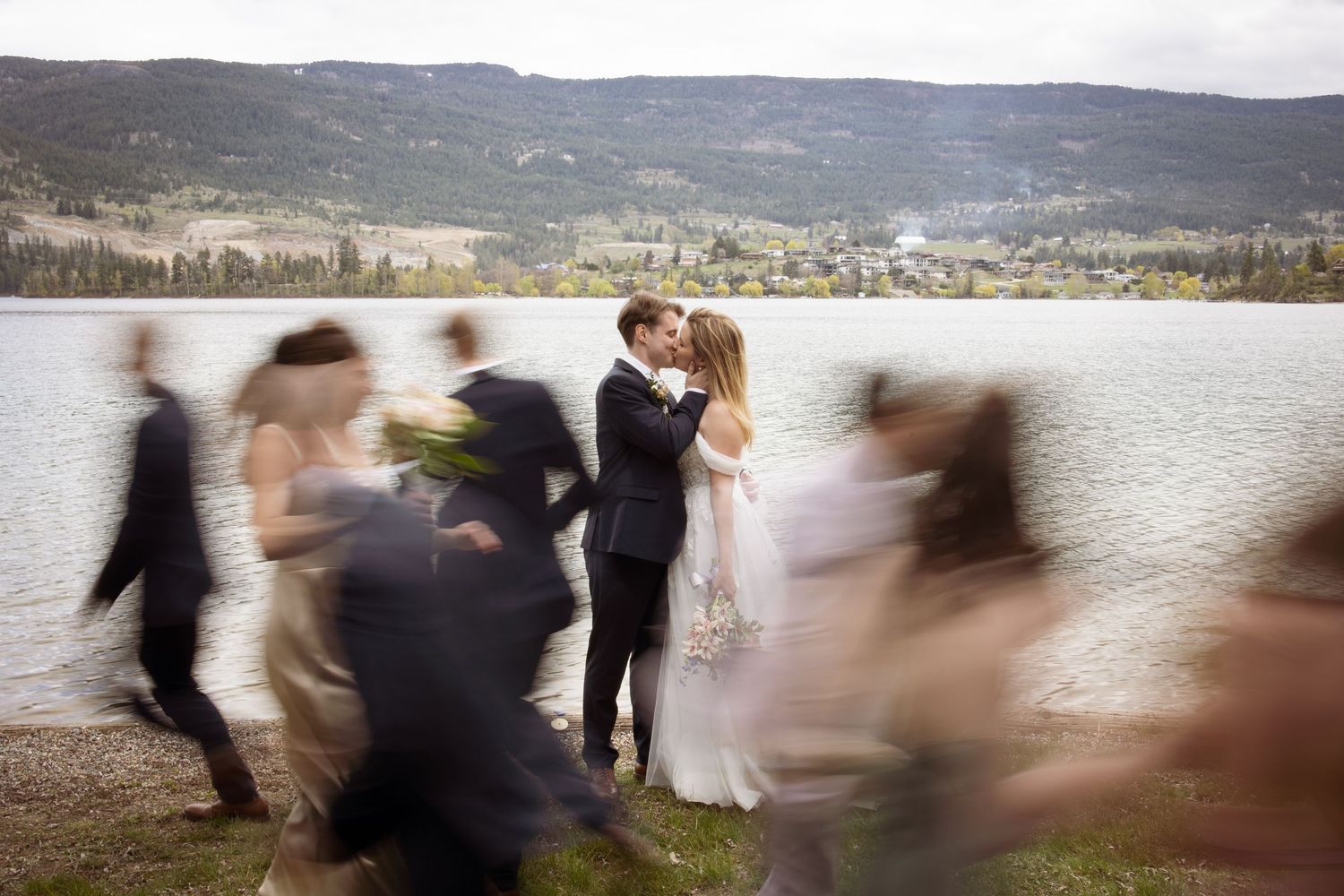 Creative wedding photo with motion blur of guests walking while couple remains in focus.