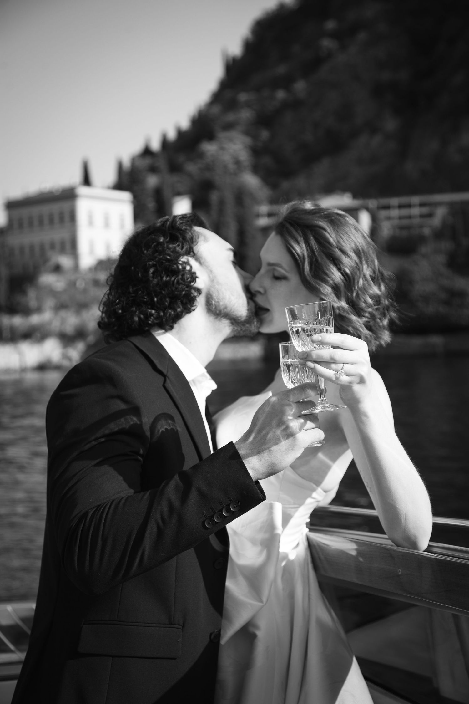 Black and white photo of couple sharing champagne toast on boat.