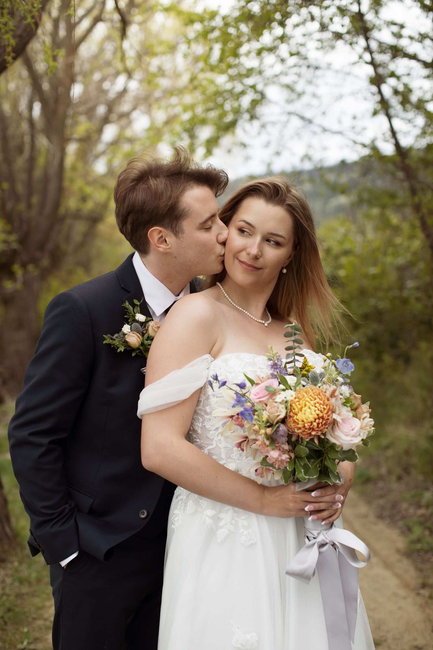 Romantic couple sharing tender moment with colorful wildflower bouquet in natural setting.