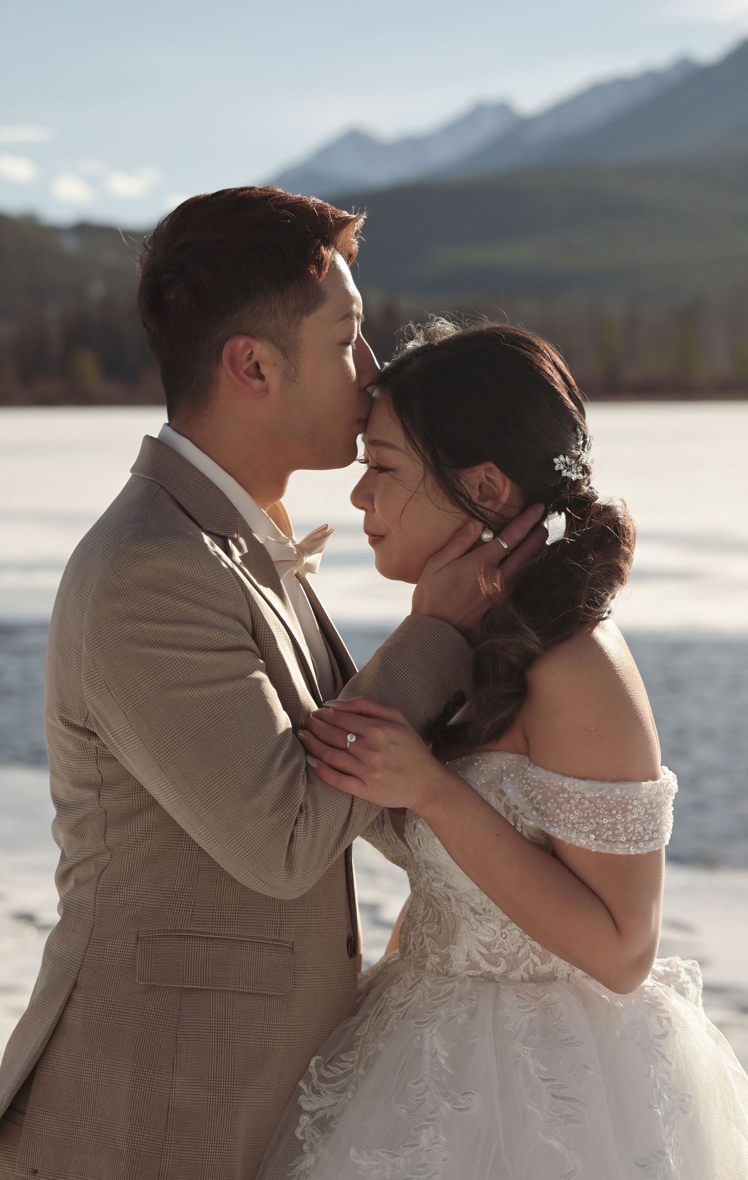 Intimate wedding portrait against mountain lake backdrop at sunset.