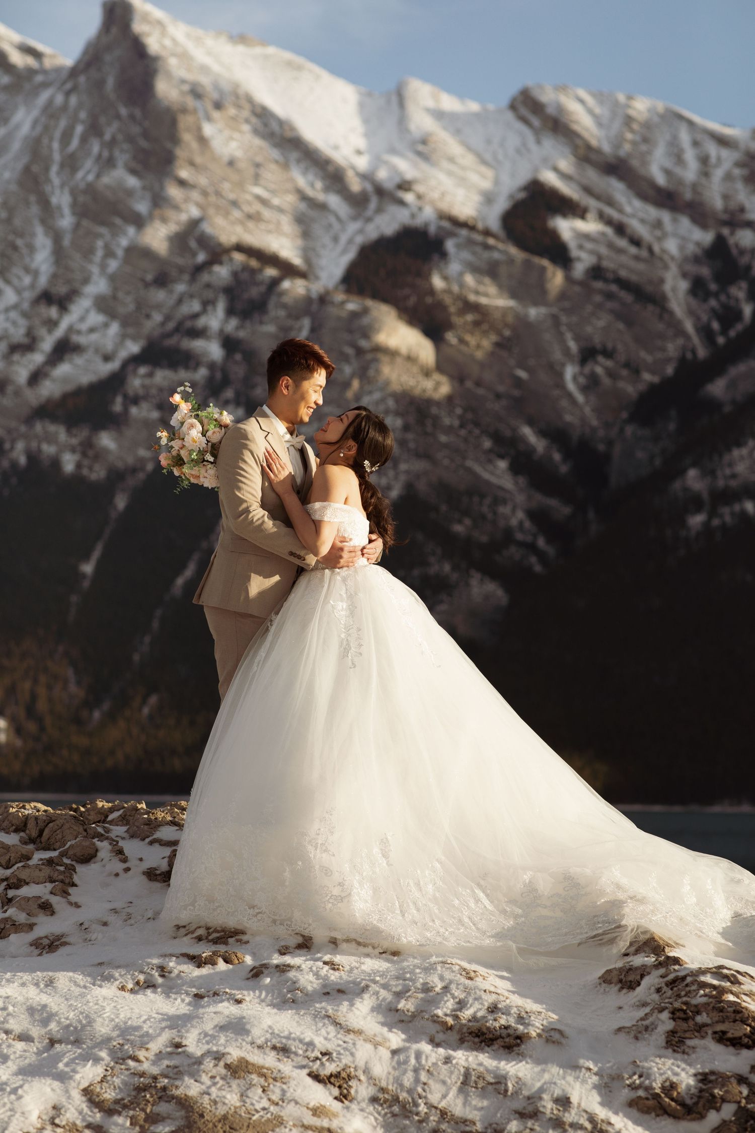 Winter wedding portrait with snow-capped mountain peaks and flowing white dress.