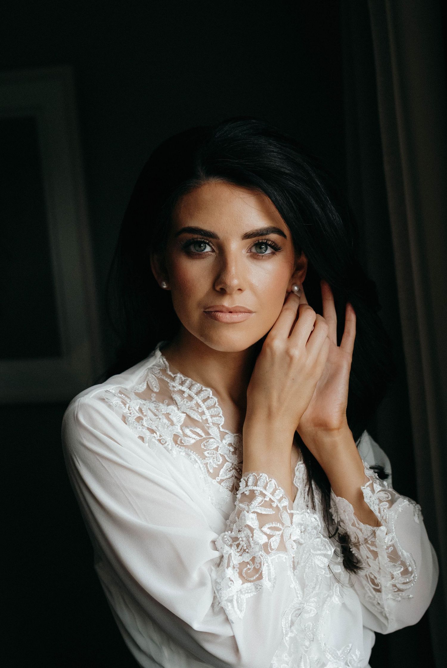 A bridal portrait sequence showing elegant white lace detailing on a wedding dress sleeve against a dark background. AdareManor