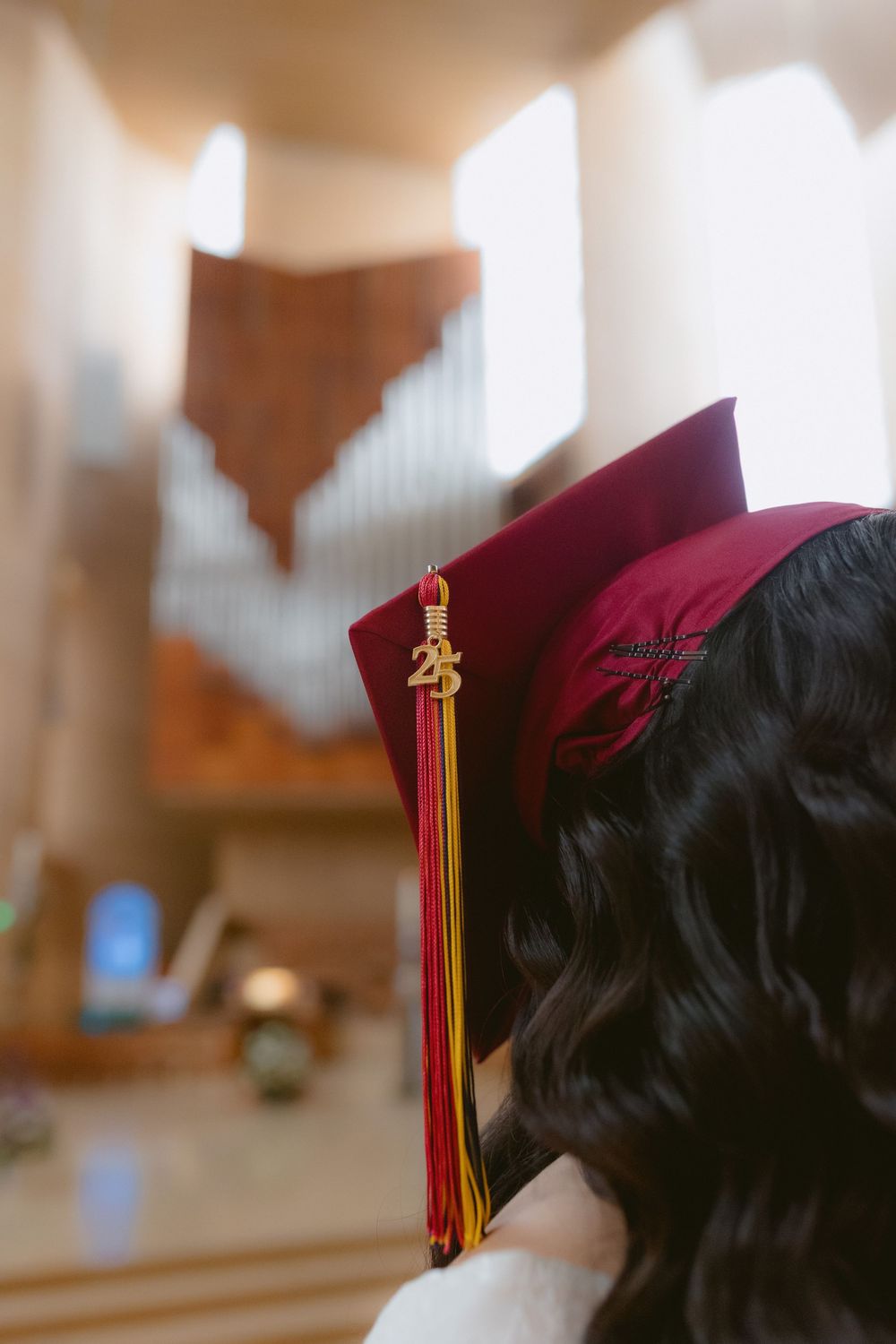 Graduation cap with burgundy tassel shown in close-up against a blurred background.