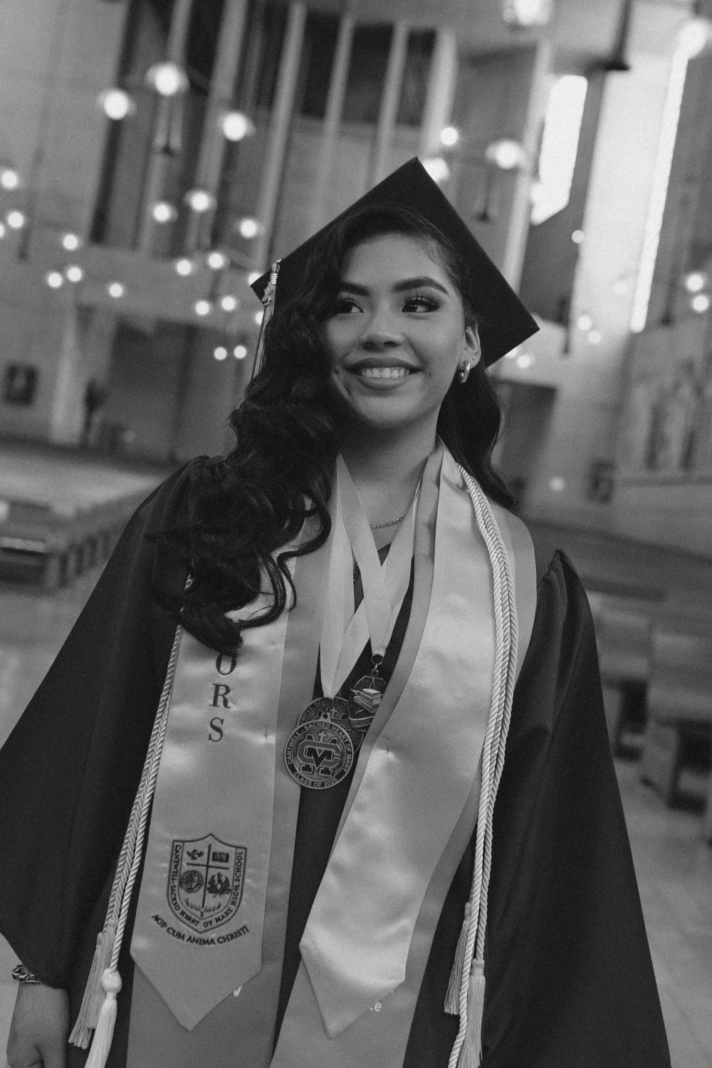 Graduate wearing black cap and gown with white stole celebrating commencement.