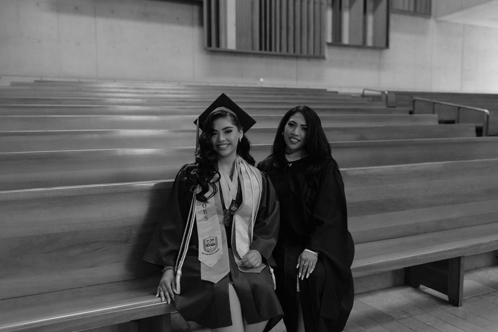 Graduates posing together in black caps and gowns after graduation ceremony.