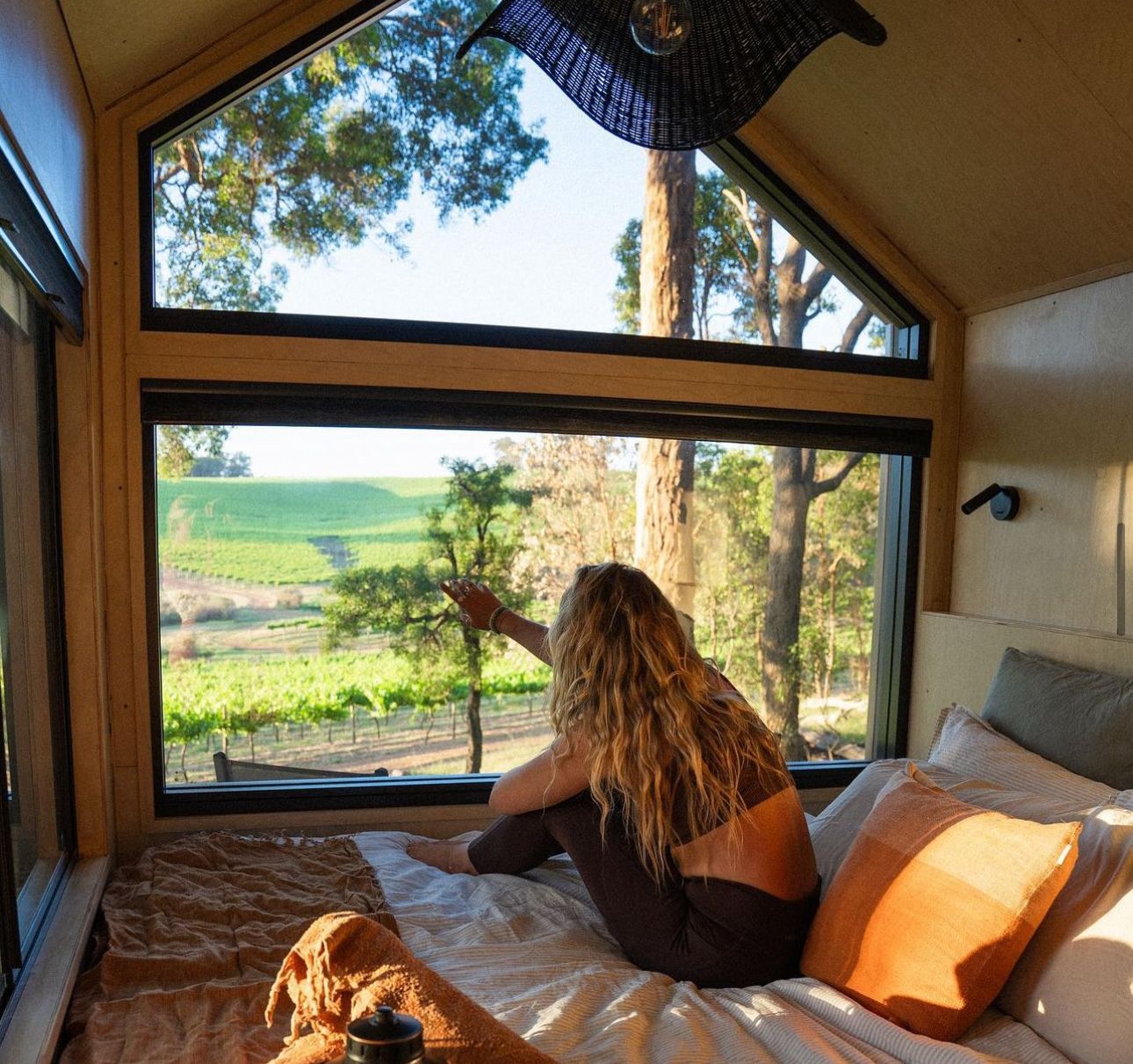 Cozy camper van interior with panoramic windows overlooking a scenic vineyard landscape.