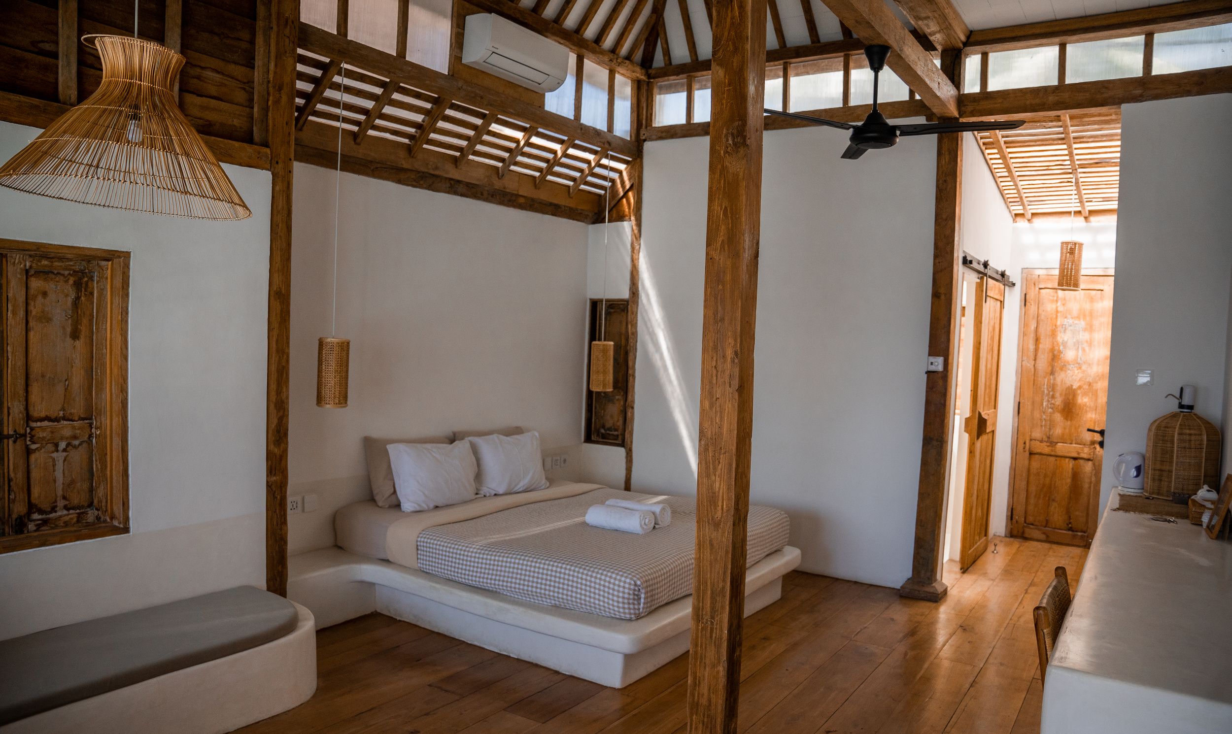 Interior view of a rustic wooden room with exposed beams and minimalist white walls.