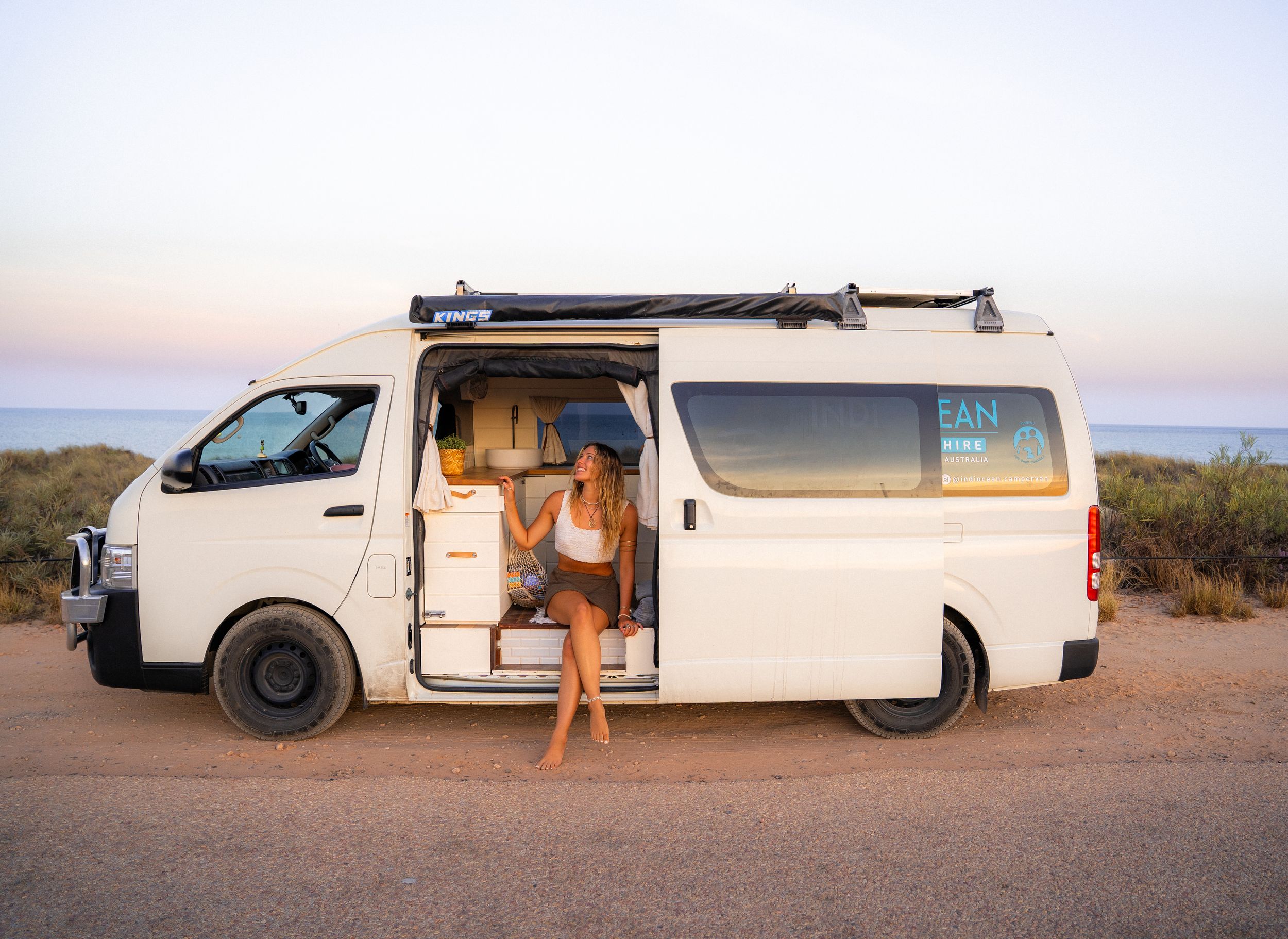 White cargo van parked in a desert setting during golden hour.