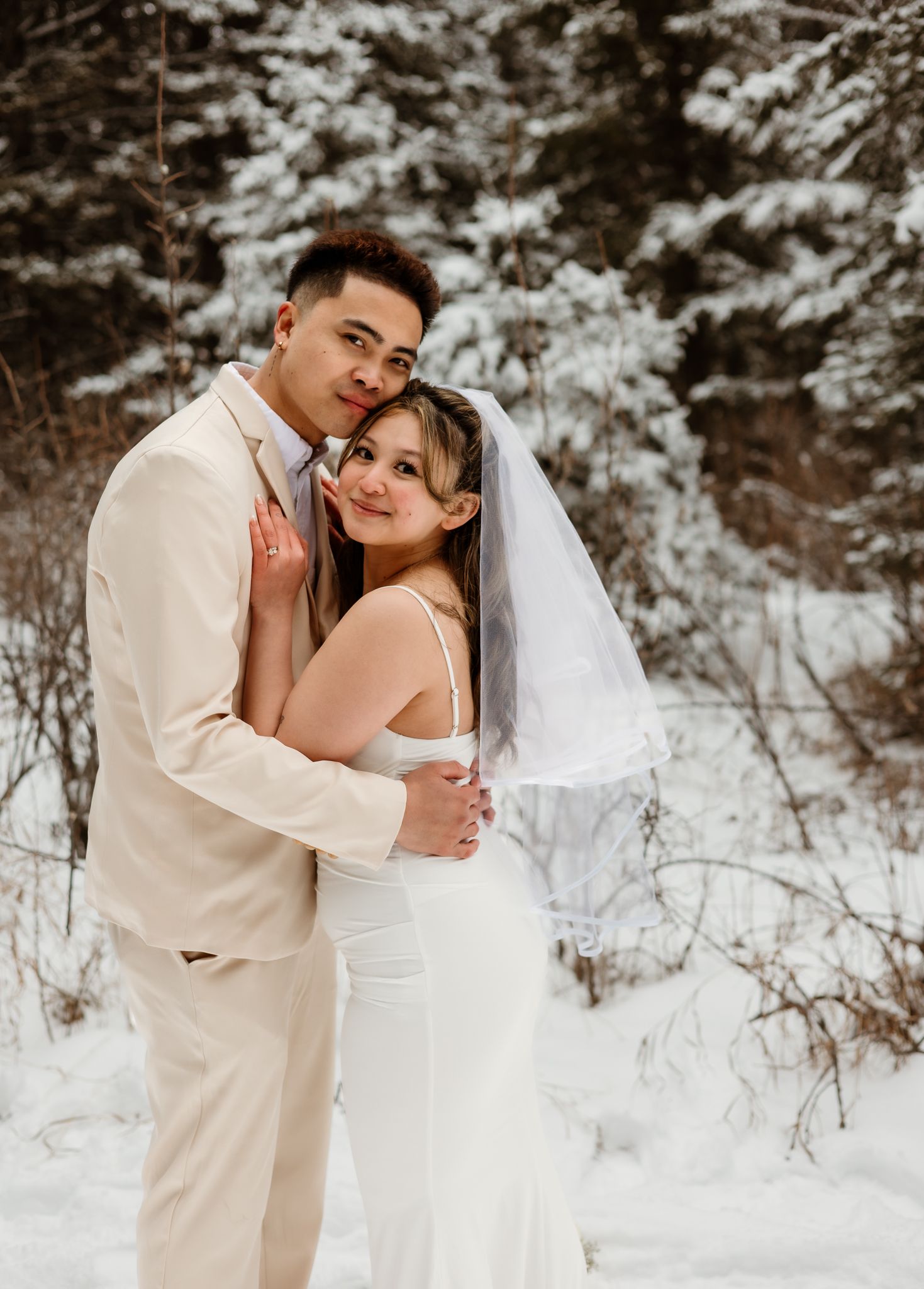 Bride and groom hugging with snowy backdrop in Calgary