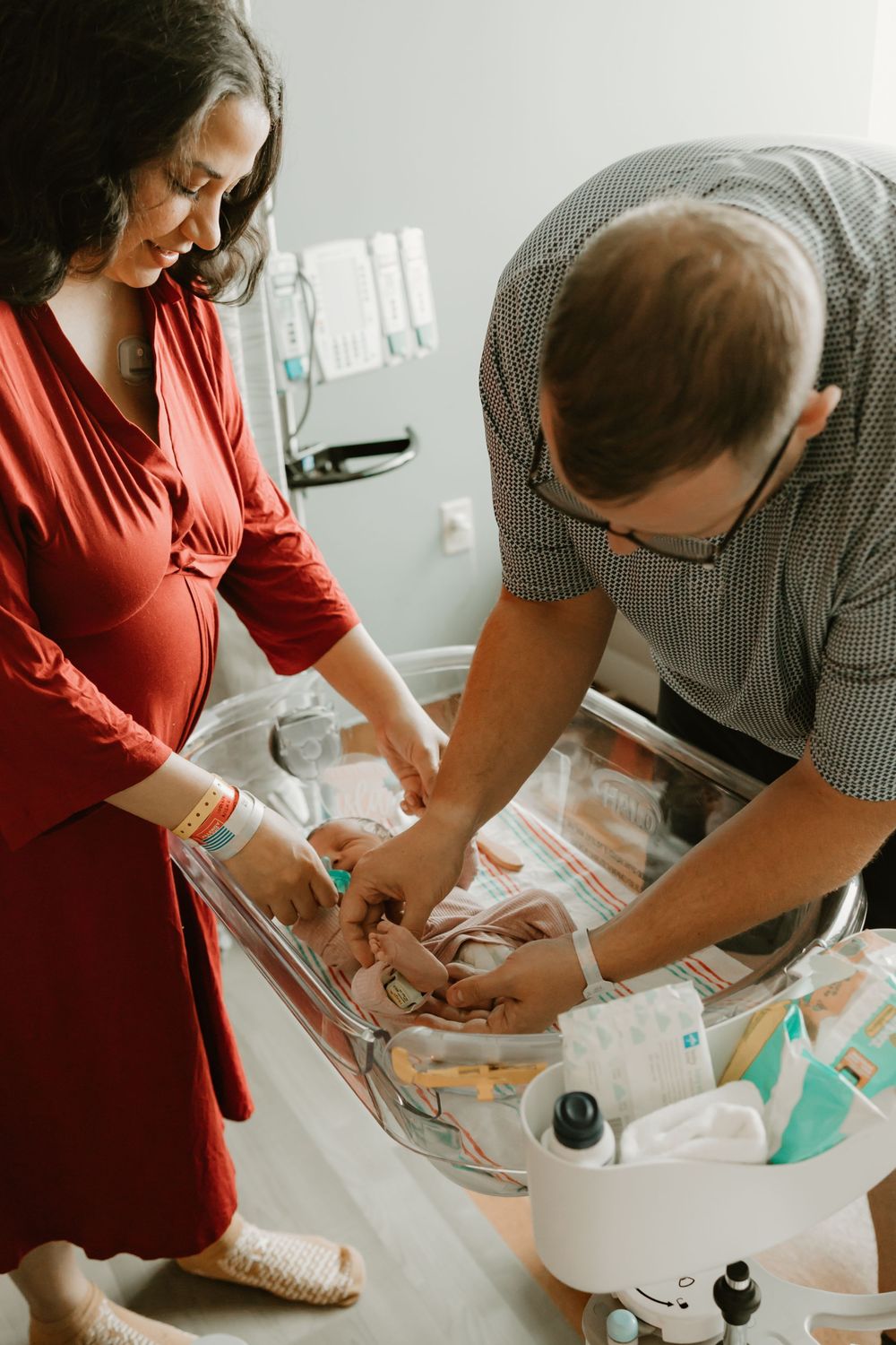 A newborn baby receives care and checkup in hospital room with medical equipment and supplies.