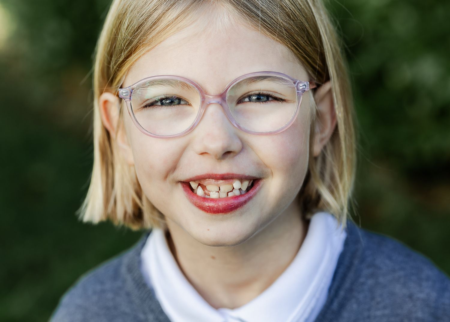 A school child stands in a park and smiles for relaxed and modern school photos outdoors. Bristol primary school photographer