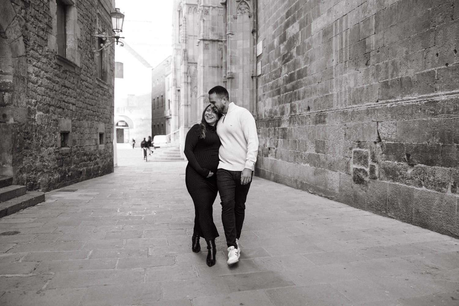 Black and white photo of a couple walking through a narrow medieval stone passage.