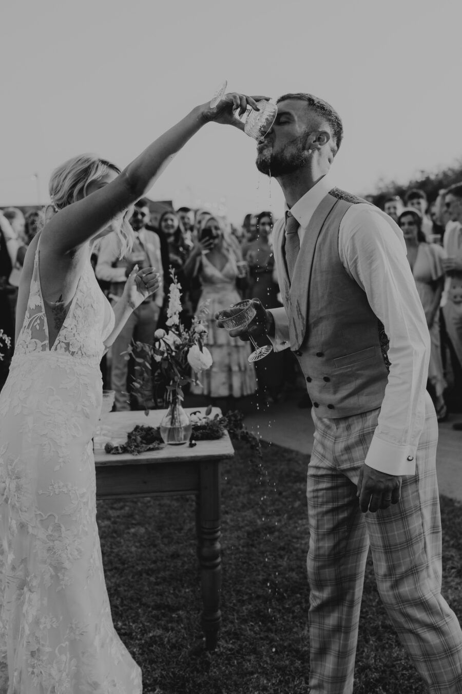 Black and white vintage photo of wedding guests standing in a field with raised arms celebrating.