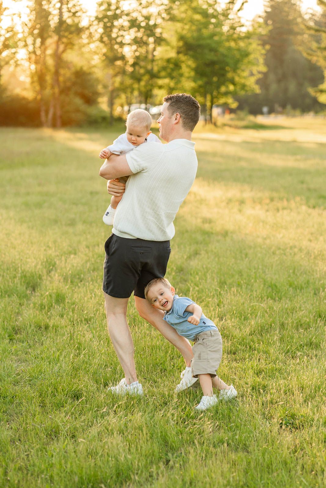 Boy head butting dad in a field at sunset.
