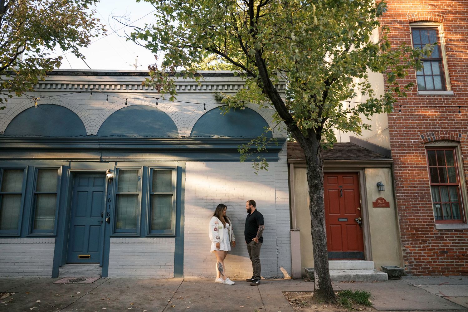 A couple stands outside a historic building with blue doors and arched details in a charming urban setting.